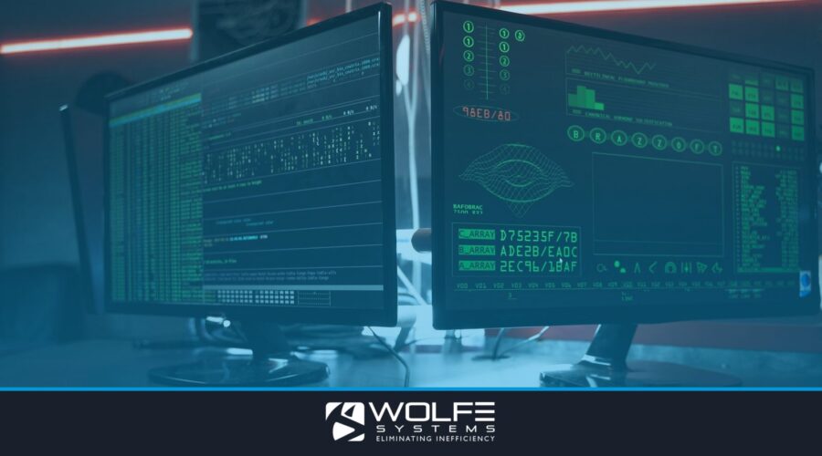Close-up of dual computer monitors with green coding interfaces in a dark room, highlighting cyber security themes.