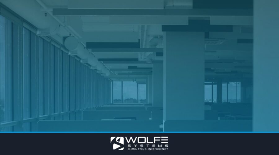 Spacious empty office with rows of desks and large windows.