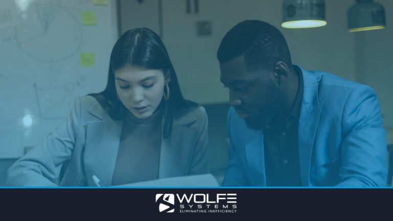 Two colleagues collaborating over documents at an office desk.